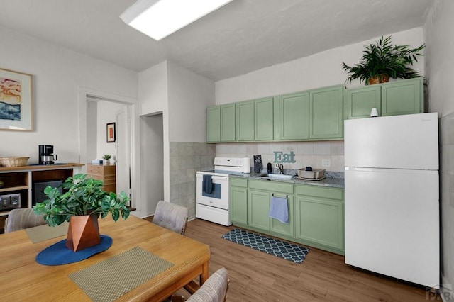 kitchen with white appliances, light countertops, a sink, light wood finished floors, and green cabinetry