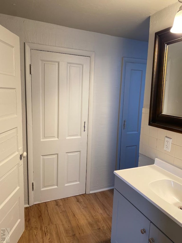 bathroom featuring wood finished floors, decorative backsplash, and vanity