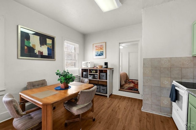 dining room with wood finished floors and tile walls