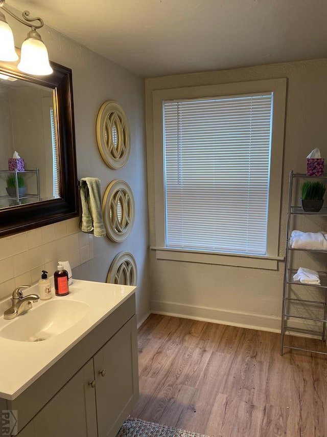 bathroom with vanity, baseboards, decorative backsplash, and wood finished floors