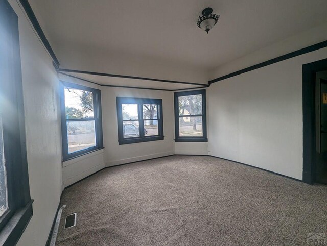 carpeted empty room featuring visible vents