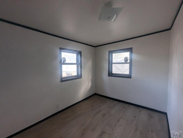 unfurnished room with light wood-style floors, plenty of natural light, ornamental molding, and baseboards