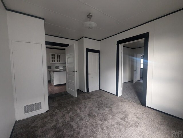 unfurnished bedroom featuring dark colored carpet and visible vents