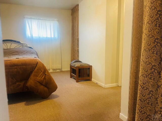 bedroom featuring light carpet and baseboards