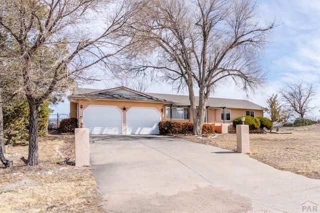 single story home featuring stucco siding, driveway, an attached garage, and fence