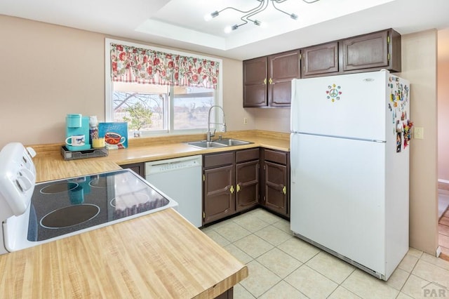 kitchen with white appliances, a tray ceiling, a sink, light countertops, and dark brown cabinets