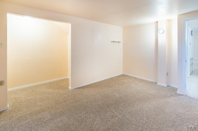 carpeted empty room featuring baseboards