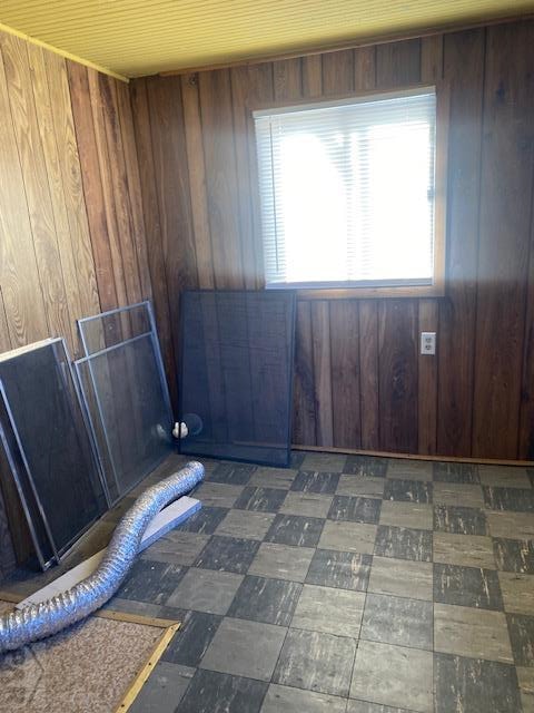 unfurnished room featuring dark floors and wooden walls