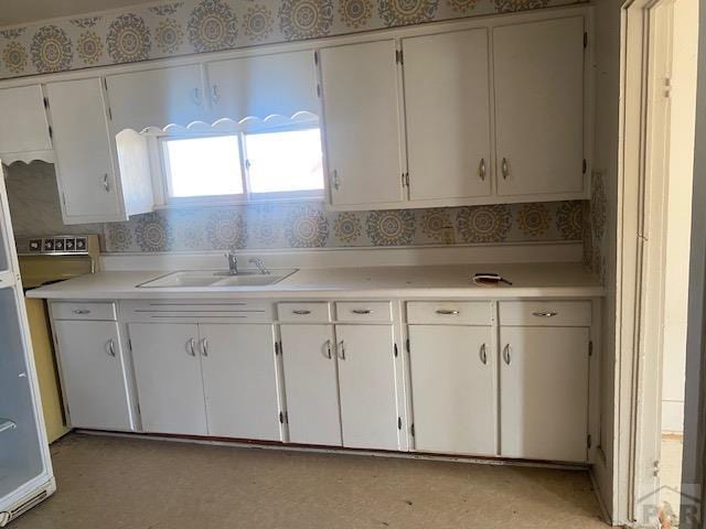 kitchen with light countertops, a sink, and white cabinetry