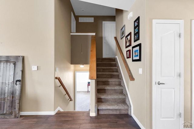 stairway with wood finished floors, visible vents, and baseboards