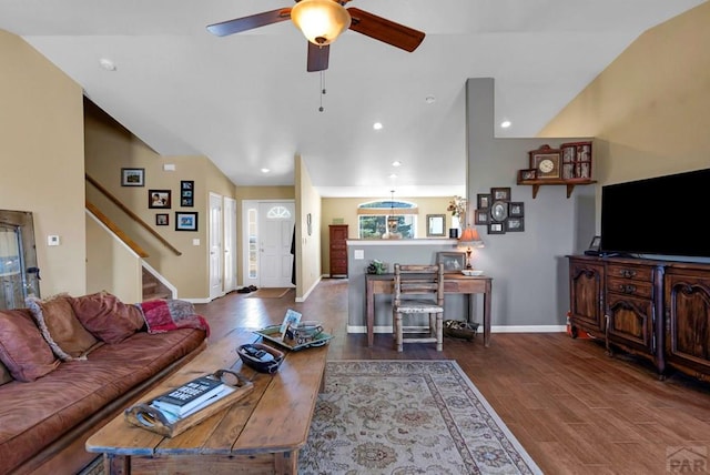 living room featuring vaulted ceiling, wood finished floors, a ceiling fan, baseboards, and stairs