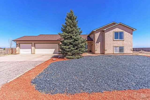 view of front of home featuring fence, driveway, stucco siding, and a garage