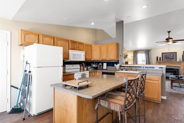 kitchen with a peninsula, dark wood-style floors, a sink, vaulted ceiling, and white appliances