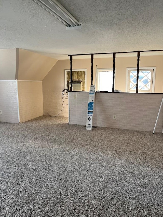 spare room with a textured ceiling, brick wall, and carpet floors