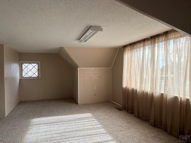 bonus room featuring visible vents, a textured ceiling, lofted ceiling, and light colored carpet