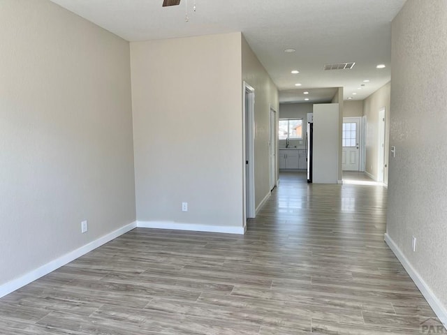 spare room with light wood finished floors, recessed lighting, visible vents, and baseboards