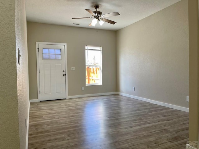 foyer entrance with dark wood-style floors, baseboards, visible vents, and ceiling fan