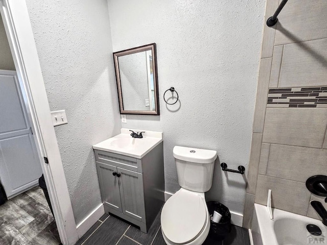 full bathroom featuring a textured wall, toilet, shower / tub combination, wood finished floors, and vanity