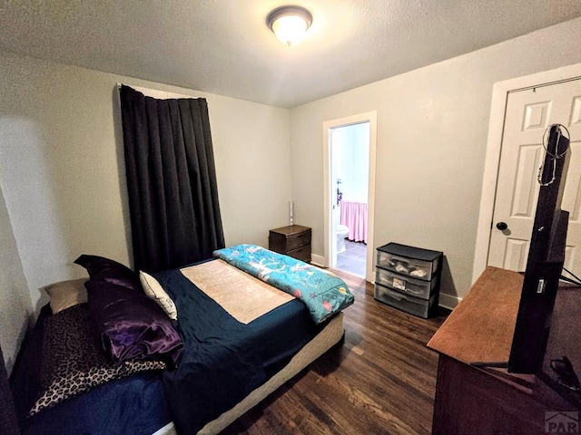 bedroom featuring dark wood-style flooring, connected bathroom, a textured ceiling, and baseboards