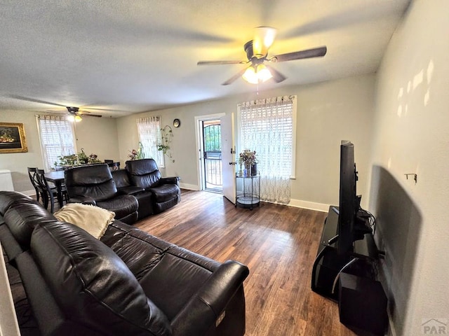 living area featuring ceiling fan, a textured ceiling, dark wood finished floors, and baseboards