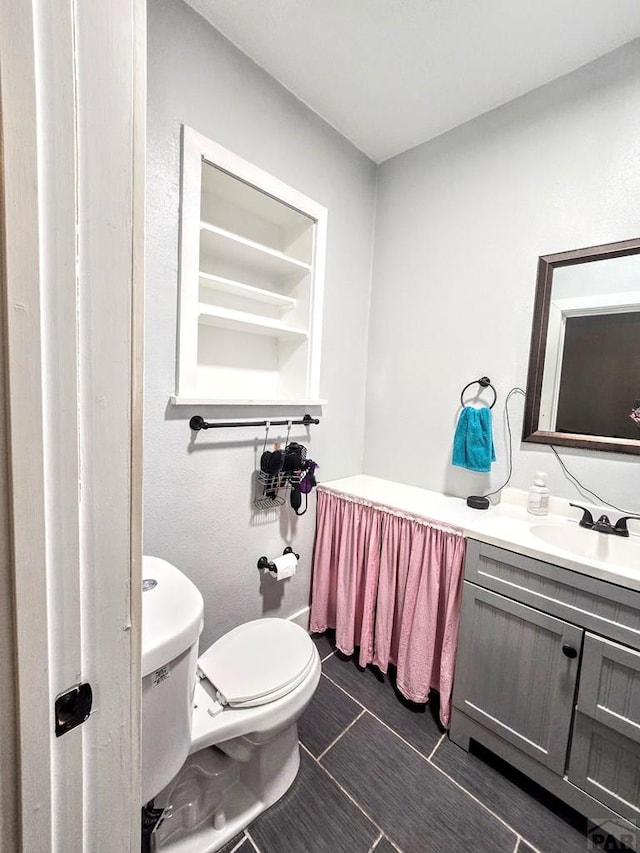 half bath featuring vanity and toilet