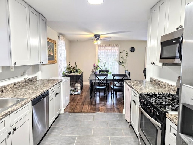 kitchen with stainless steel appliances, white cabinetry, light wood-style floors, and a ceiling fan