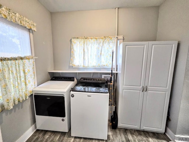 clothes washing area featuring separate washer and dryer, dark wood-style flooring, cabinet space, and baseboards