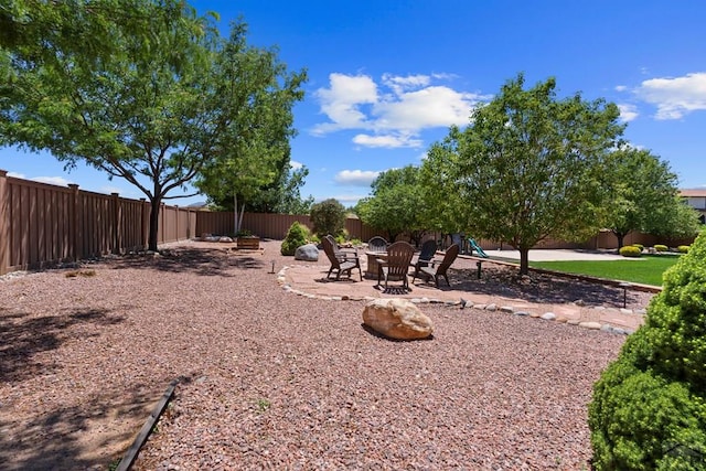 view of yard with a fenced backyard, a fire pit, and a patio