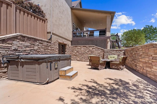 view of patio / terrace with a hot tub and stairs