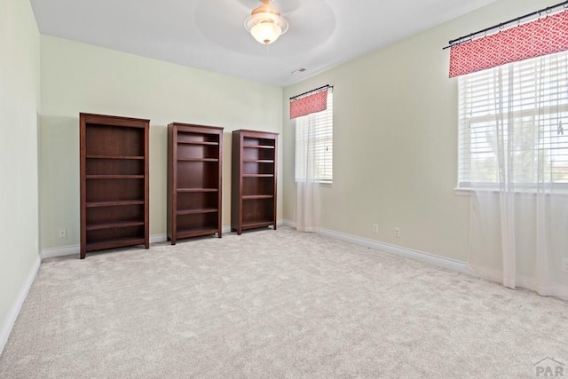 unfurnished bedroom featuring light carpet, a ceiling fan, and baseboards