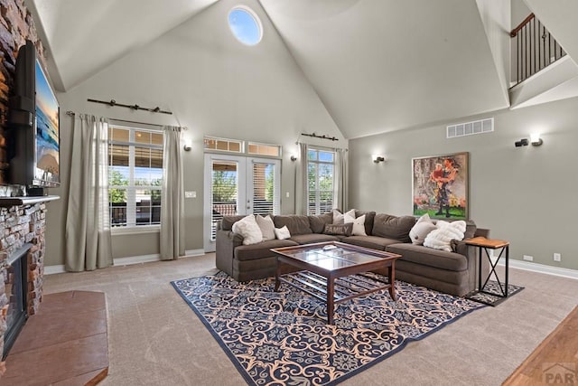 living area with a fireplace, visible vents, light carpet, high vaulted ceiling, and baseboards