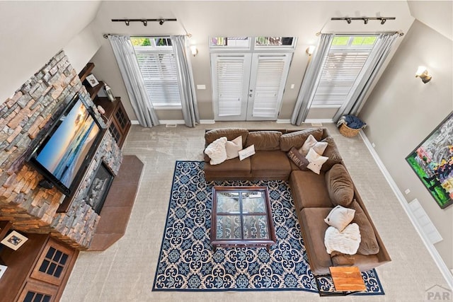 living room with a fireplace with flush hearth, french doors, a healthy amount of sunlight, and baseboards