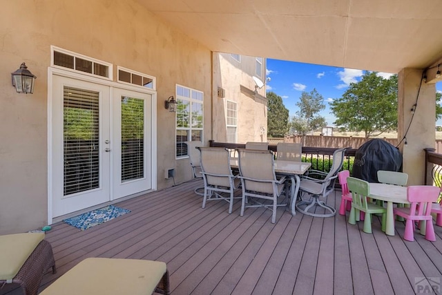 wooden terrace with outdoor dining space, french doors, and fence