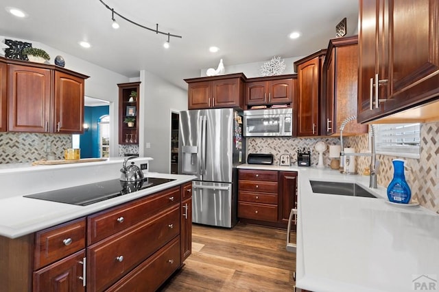 kitchen featuring tasteful backsplash, appliances with stainless steel finishes, light countertops, light wood-type flooring, and a sink