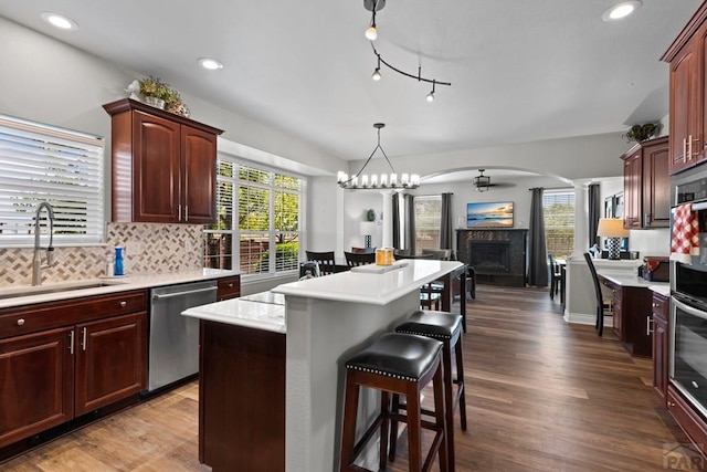 kitchen with arched walkways, open floor plan, light countertops, stainless steel dishwasher, and a sink