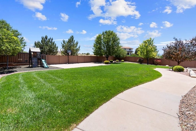 view of yard featuring a fenced backyard, a playground, and a patio