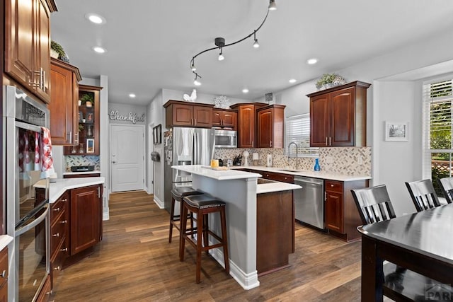 kitchen with a breakfast bar, a sink, light countertops, appliances with stainless steel finishes, and a center island