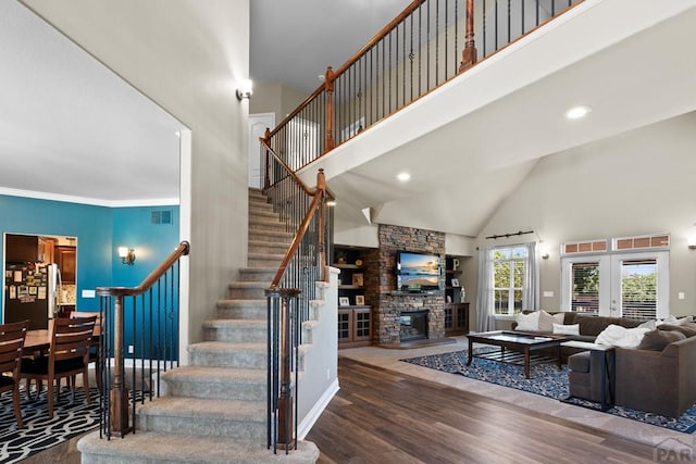 living room with visible vents, a towering ceiling, stairway, wood finished floors, and a fireplace