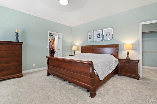 bedroom featuring light carpet, a spacious closet, baseboards, and a closet