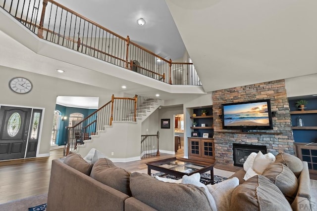 living room with a fireplace, wood finished floors, built in features, stairs, and baseboards