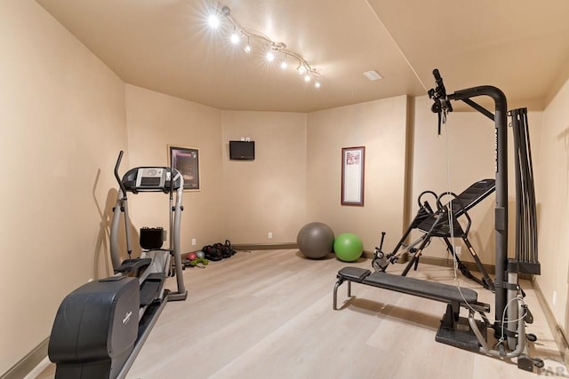 exercise area with light wood-style floors and baseboards