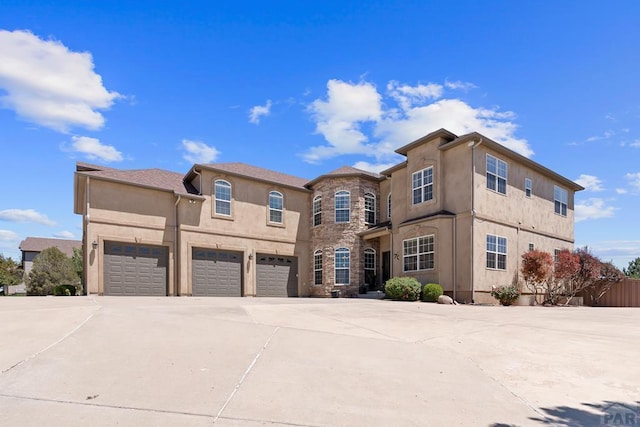 view of front of property with driveway, stone siding, a garage, and stucco siding