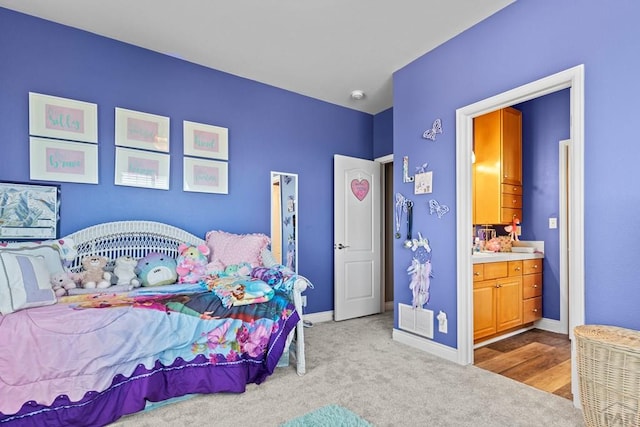 bedroom featuring light colored carpet, ensuite bath, and baseboards