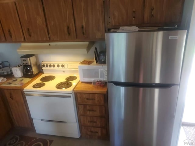 kitchen featuring white appliances, brown cabinetry, and wooden counters