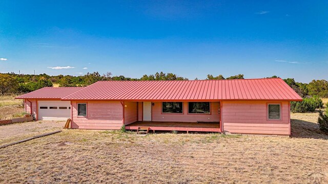 ranch-style house with a garage, metal roof, and driveway