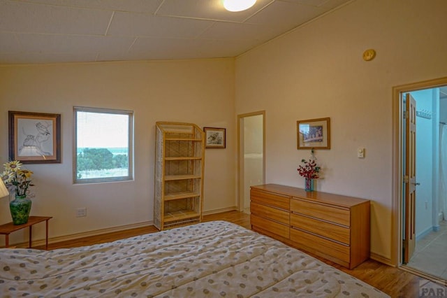 unfurnished bedroom with light wood-style floors, vaulted ceiling, and baseboards