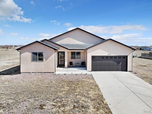 single story home featuring concrete driveway, roof with shingles, an attached garage, and stucco siding