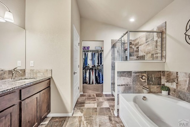 full bathroom with a spacious closet, a shower stall, vanity, baseboards, and a bath