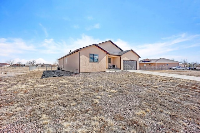 view of front of property featuring a garage, concrete driveway, fence, and stucco siding