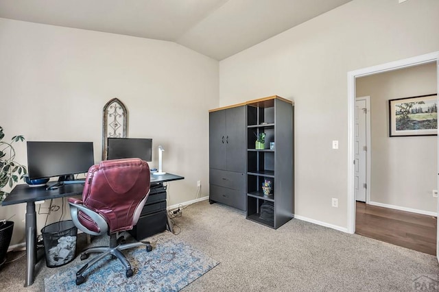 carpeted office space with lofted ceiling and baseboards